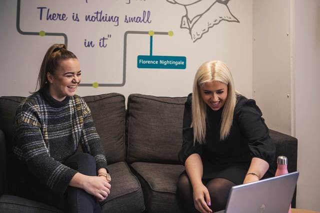 Two people on a sofa laughing at a laptop
