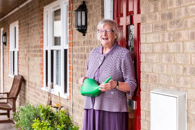 Woman outside house with watering can