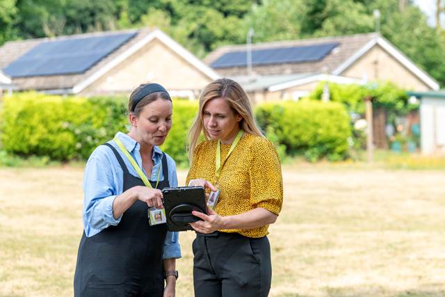 Two people talking while looking at a tablet