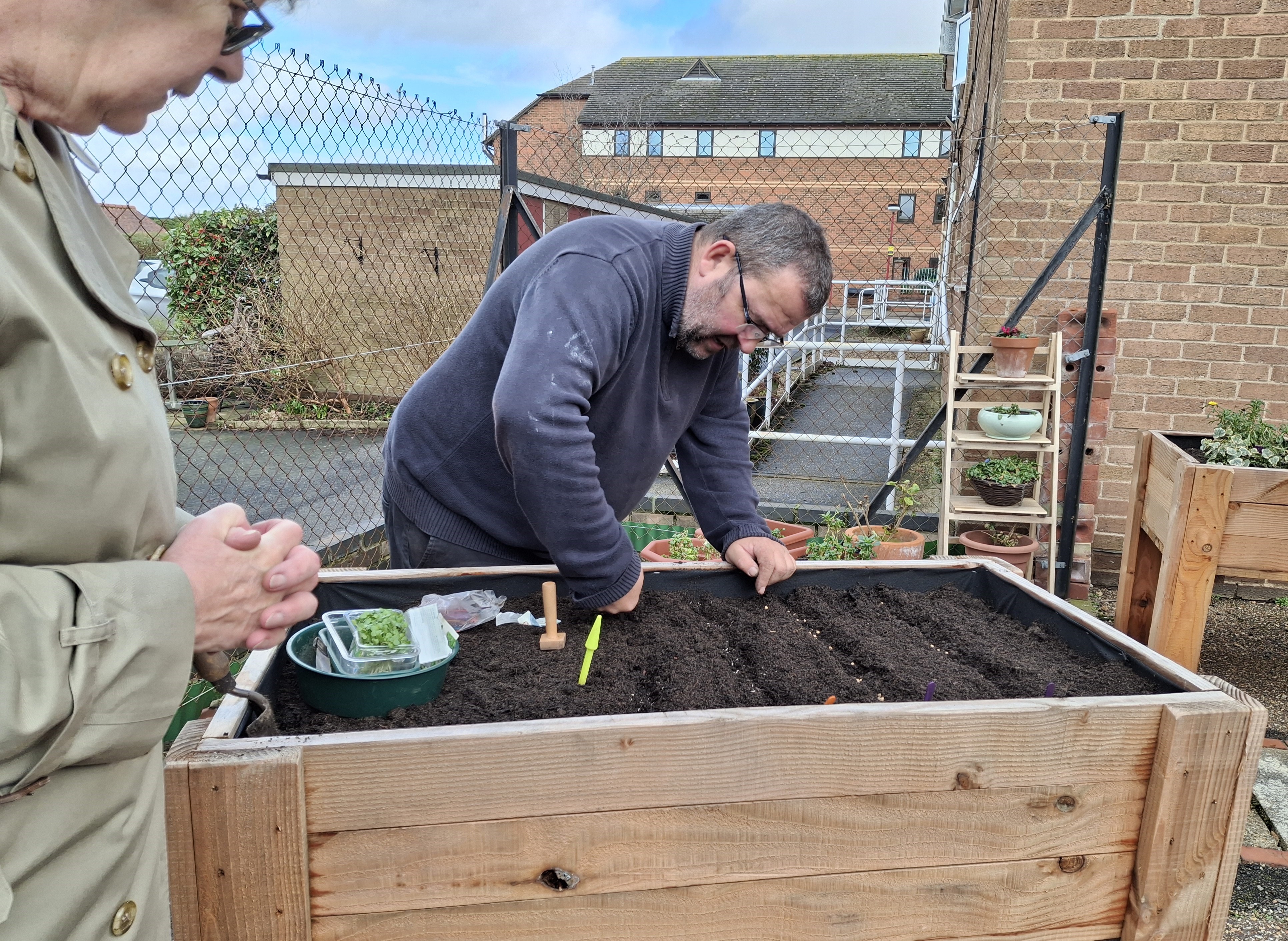 Chris Collins leads by example on sowing plants into one of the handmade planter containers at the Courtyard Gardens in North Walsham