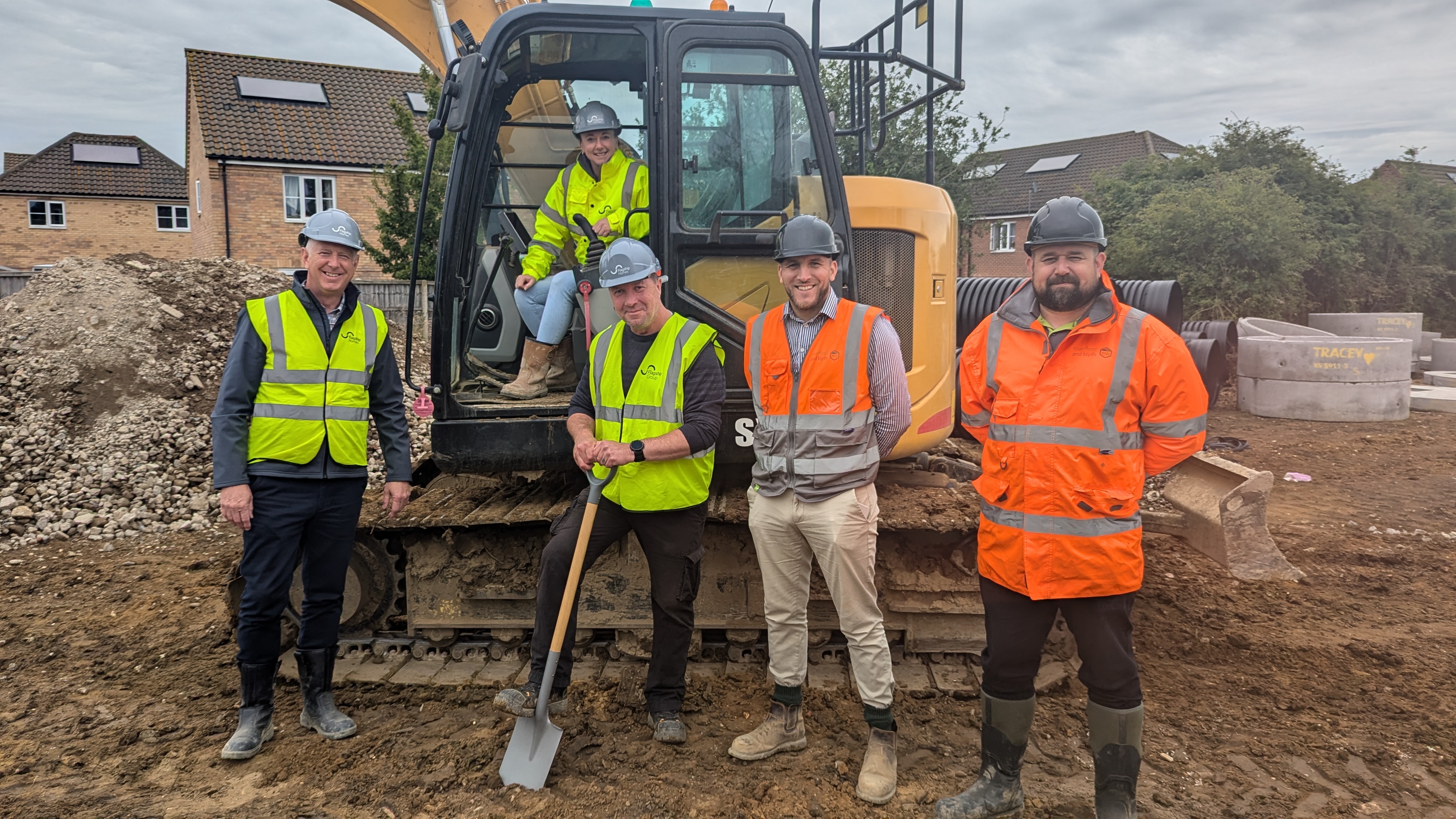 1. L-R Flagship Homes’ MD Tony Tann, head of partnerships Anna Cook-Bacon, and project manager Simon Floor with Marfleet & Blyth’s construction manager Kyle Crush and site manager Jamie Kirk pose in front of a digger at the Station View development in Vince’s Road, Diss